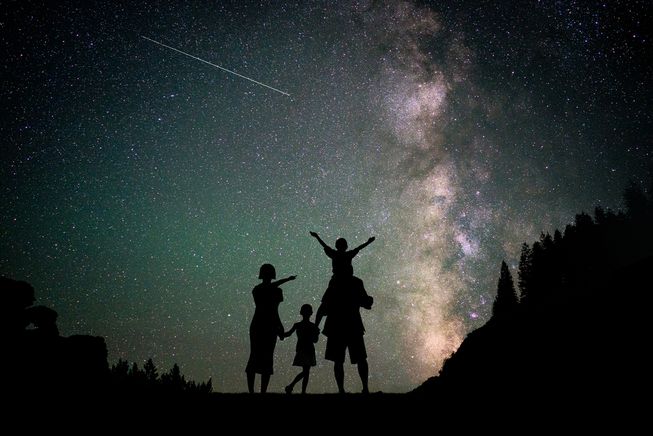 Family watches the stars beneath the milky way galaxy